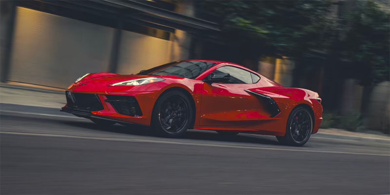 A red Chevrolet Corvette Stingray in running on a road, with blurred greenery
