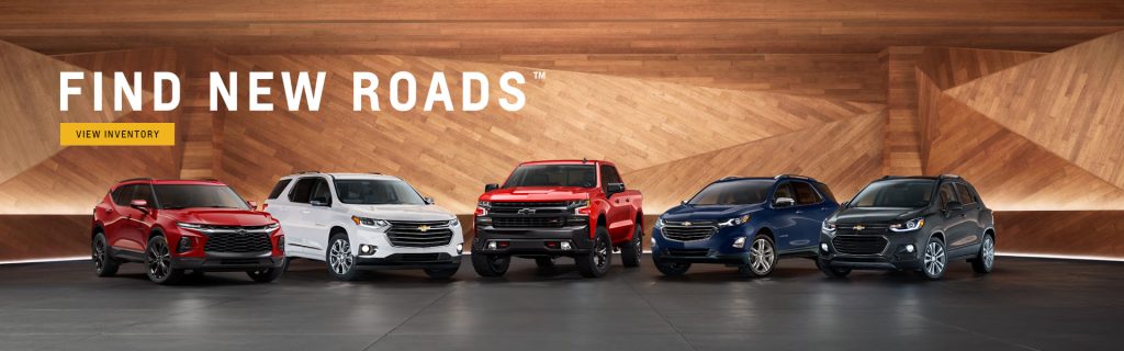 Chevrolet new vehicle lineup showcasing SUVs and a pickup truck in a modern showroom with ‘Find New Roads’ campaign, highlighting performance, versatility, and advanced technology across Chevy models.