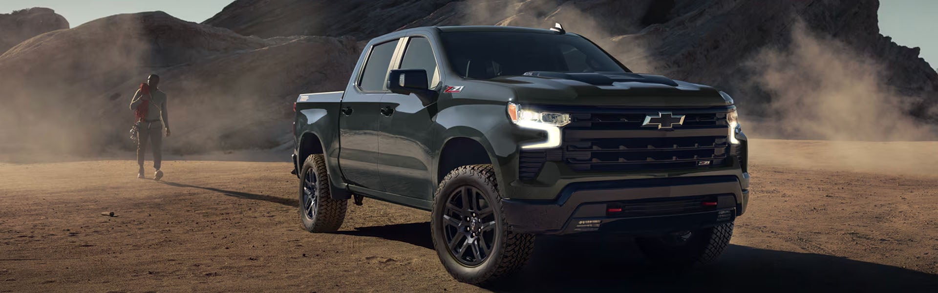Grey Silverado 1500 standing in a dusty area surrounded by mountains.