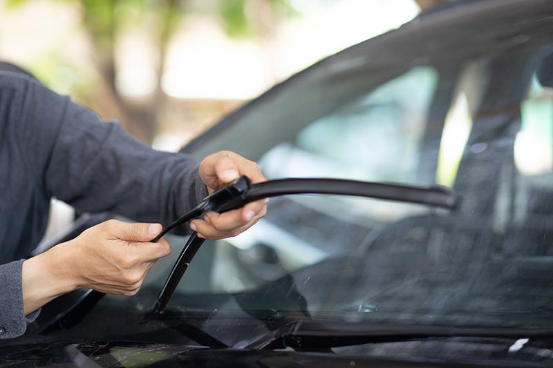 mechanic changing wiper blades on car